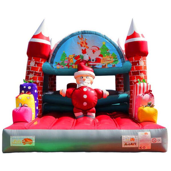 Un CHÂTEAU GONFLABLE PÈRE NOËL coloré et gonflable conçu comme un château avec des tours rouges et blanches. Il a un thème festif du Père Noël, avec une grande figurine du Père Noël à l'entrée et des cadeaux autour de lui. L'arche supérieure présente des décorations de Noël et un panneau « Joyeux Noël ».