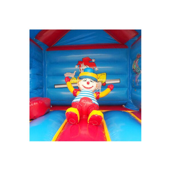 Une maison gonflable gonflable présente une figure de clown joyeuse et colorée au centre avec les bras tendus. L'intérieur est d'un bleu vif avec des accents rouges et jaunes, créant une atmosphère festive et ludique.